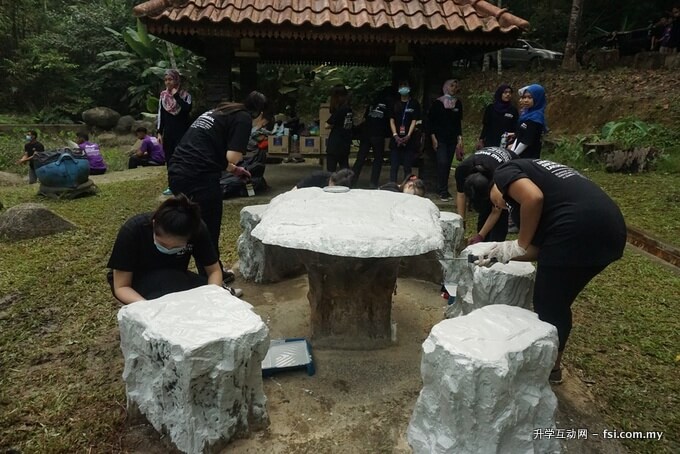 Student volunteers from INTI International University painting a sitting area at the Ulu Bendul Forest Reserve site.