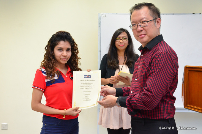 Dr Teh presenting a certificate to Nur Amelia while Dr Alia (back) looks on.