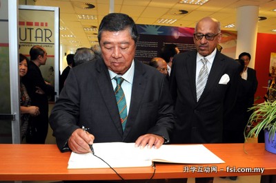 Tun Ling signing the guest book while Tan Sri V.C. George looks on.