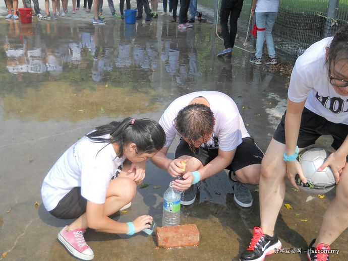 Participants squeezing water from a sponge into the bottle.