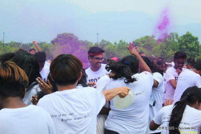 Participants spattering handfuls of coloured powder and drenching each other in water.