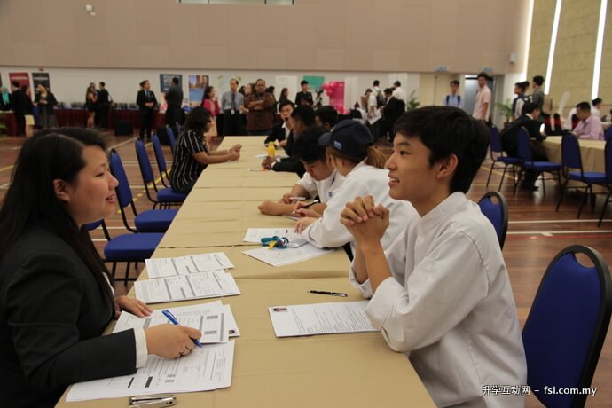 陈蔚宏（右），目前在伯乐就读烹饪艺术文凭课程，图示他在就业展上接受即场面试。