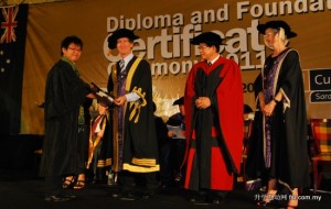 Chancellor Dr. Jim Gill presenting a diploma graduate his award as Datuk Lee Kim Shin and Professor Jeanette Hacket look on