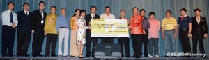 Prof Chuah handing over the mock cheque to Tan Chin Siang under the witness of Tun Dr Ling while special guests look on.