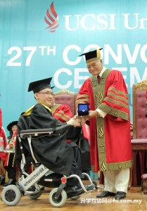 张基义（左）——患有第二型脊髓性肌肉萎缩症的UCSI学生——在UCSI大学第27届毕业典礼上从名誉校长丹斯里拿督斯里阿都拉曼阿尔斯哈（右）手中接收今年首创的名誉校长金牌奖。